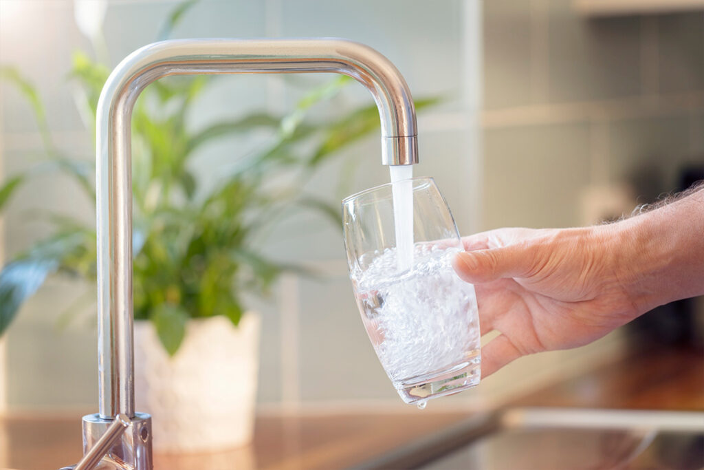 Filling up glass at sink to demonstrate water quality.